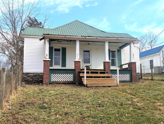 view of front of house featuring a porch, a front yard, metal roof, and fence