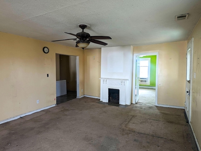 unfurnished living room featuring visible vents, a fireplace with flush hearth, ceiling fan, a textured ceiling, and carpet flooring