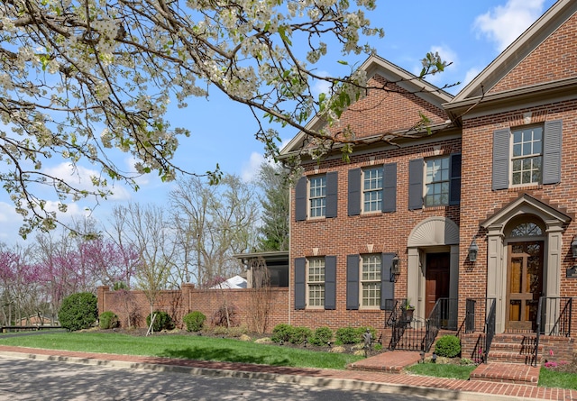 colonial home with fence and brick siding