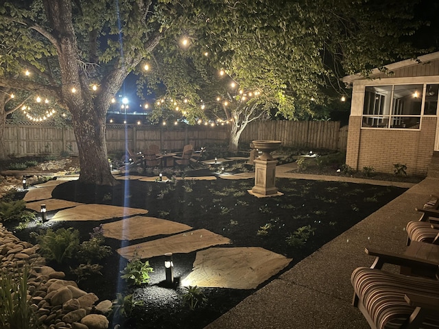 yard at night featuring a fenced backyard