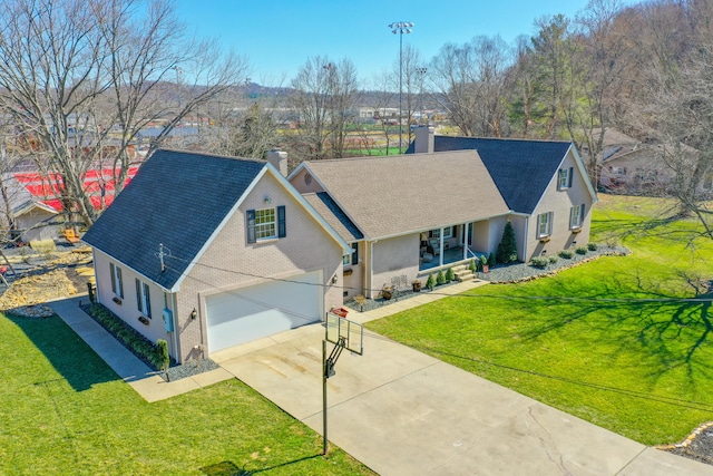 view of front of home with a porch, a chimney, concrete driveway, a garage, and a front yard