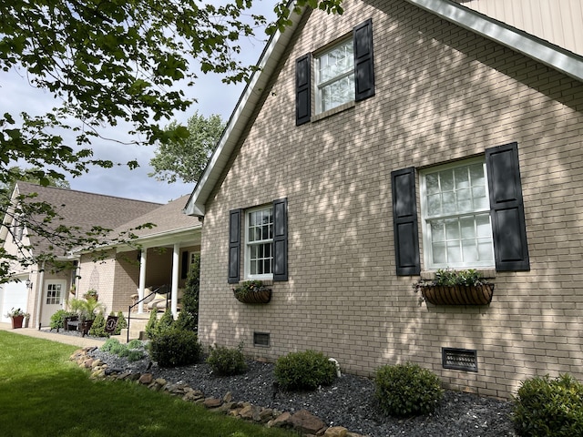 view of side of home with brick siding, crawl space, and a yard