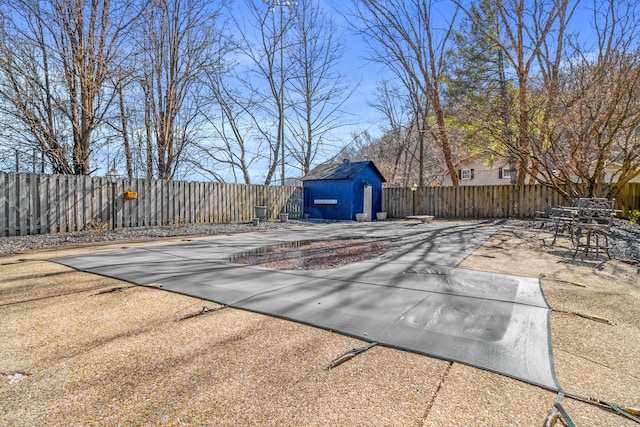 view of patio with a fenced backyard, a storage shed, and an outbuilding