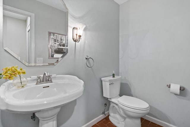 half bath with toilet, a sink, and baseboards
