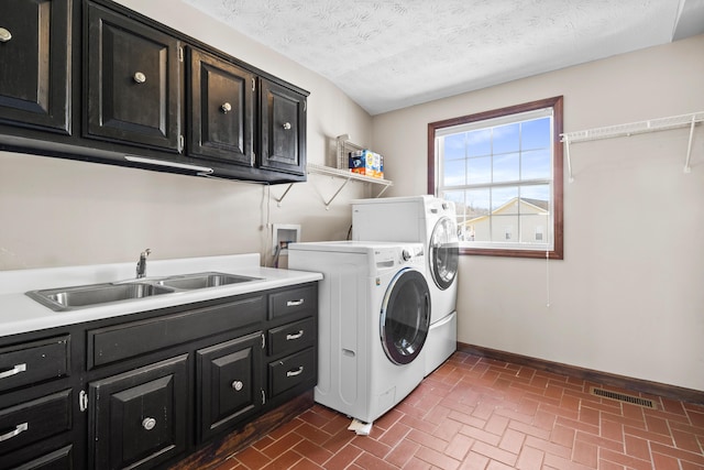 laundry room with washer and clothes dryer, cabinet space, brick patterned flooring, baseboards, and a textured ceiling