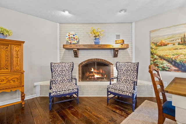 sitting room with hardwood / wood-style floors, a fireplace, baseboards, and a textured ceiling