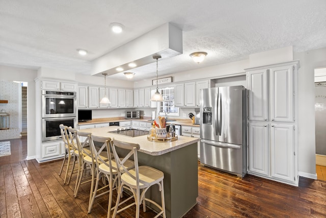 kitchen featuring stainless steel appliances, light countertops, dark wood-type flooring, white cabinetry, and a textured ceiling