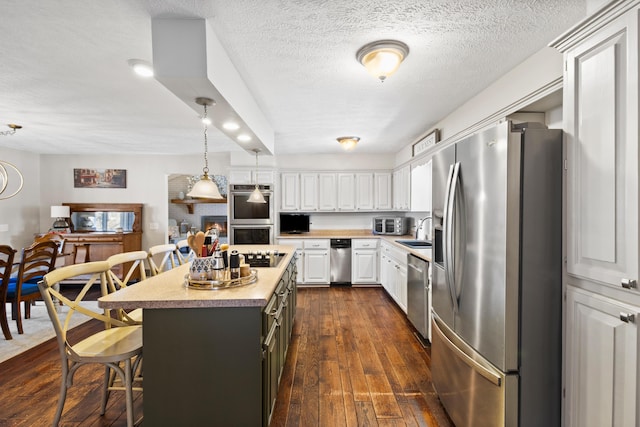 kitchen featuring appliances with stainless steel finishes, light countertops, white cabinetry, a breakfast bar area, and a sink
