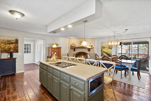 kitchen with a textured ceiling, dark wood-type flooring, black electric cooktop, a kitchen island, and light countertops