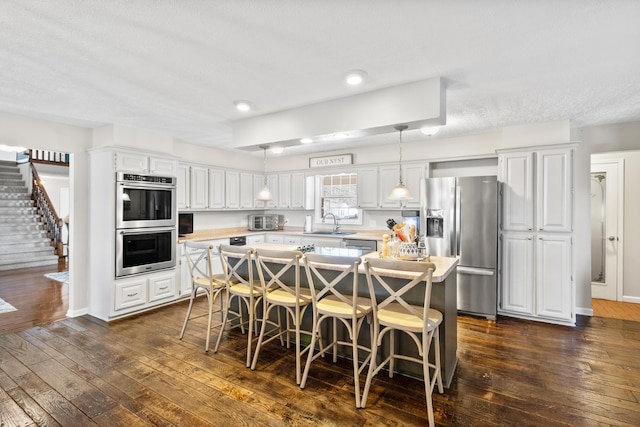kitchen with appliances with stainless steel finishes, light countertops, a sink, white cabinetry, and a textured ceiling