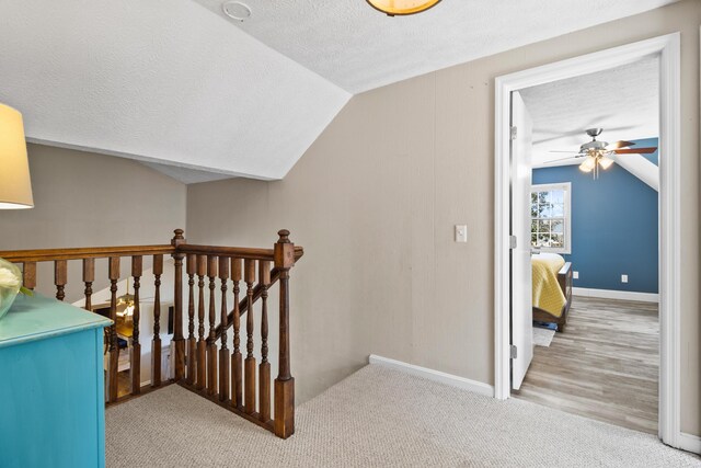 stairway featuring lofted ceiling, a textured ceiling, ceiling fan, baseboards, and carpet floors