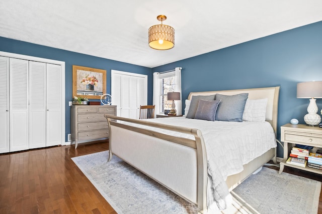 bedroom featuring multiple closets, wood-type flooring, and baseboards