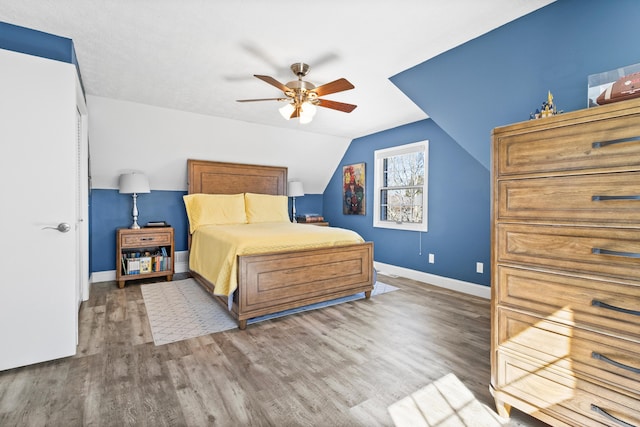 bedroom featuring wood finished floors, baseboards, lofted ceiling, and ceiling fan