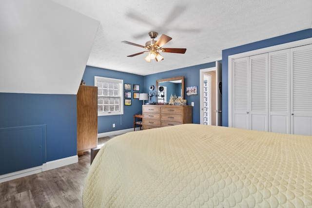 bedroom featuring wood finished floors, baseboards, a closet, a textured ceiling, and ceiling fan