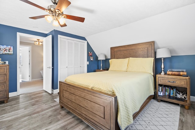 bedroom featuring wood finished floors, a closet, baseboards, ceiling fan, and vaulted ceiling