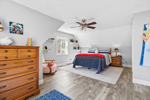 bedroom with baseboards, wood finished floors, lofted ceiling, and a ceiling fan