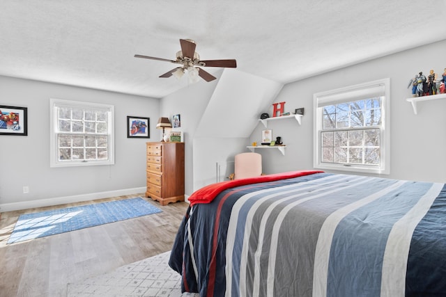 bedroom featuring multiple windows, wood finished floors, baseboards, a textured ceiling, and a ceiling fan