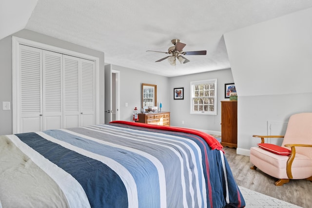 bedroom with wood finished floors, a ceiling fan, baseboards, and a closet