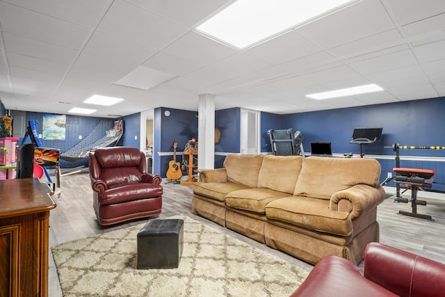 living room featuring wood finished floors, a paneled ceiling, baseboards, and a desk