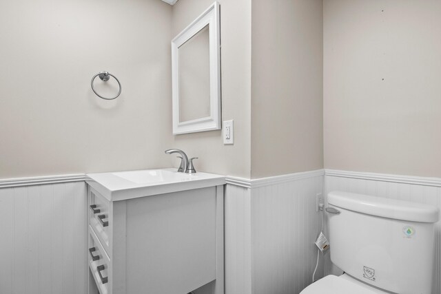 bathroom with a wainscoted wall, toilet, and vanity