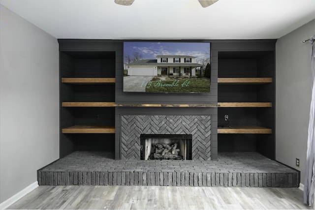 unfurnished living room with a brick fireplace, baseboards, and wood finished floors