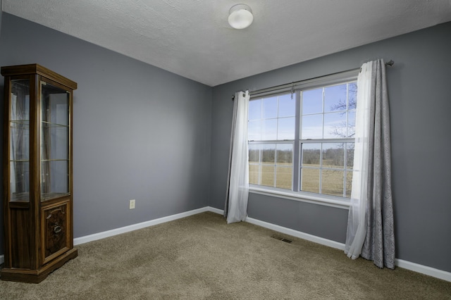 unfurnished room featuring a textured ceiling, carpet, visible vents, and baseboards