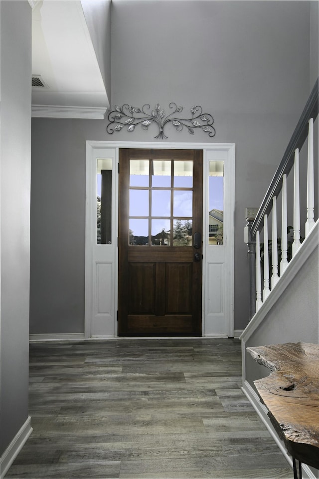 entrance foyer with crown molding, visible vents, wood finished floors, baseboards, and stairs