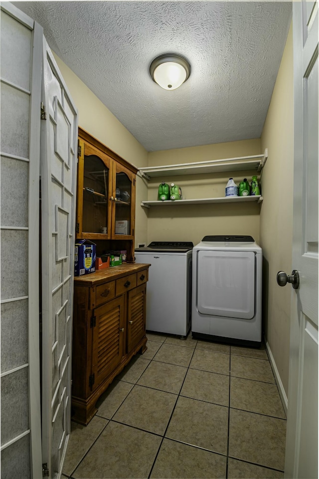 laundry area with light tile patterned flooring, a textured ceiling, separate washer and dryer, laundry area, and baseboards