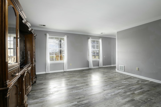 empty room with baseboards, dark wood finished floors, visible vents, and crown molding