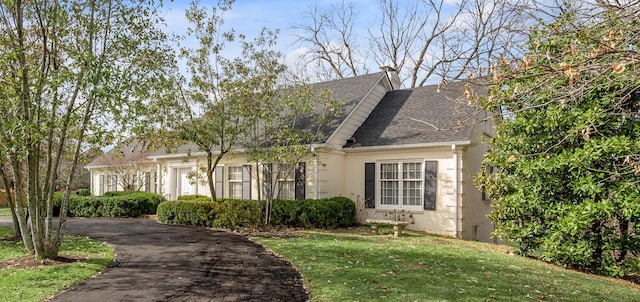 new england style home with brick siding, a shingled roof, and a front yard