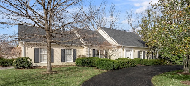 cape cod house featuring brick siding, a front yard, and a shingled roof