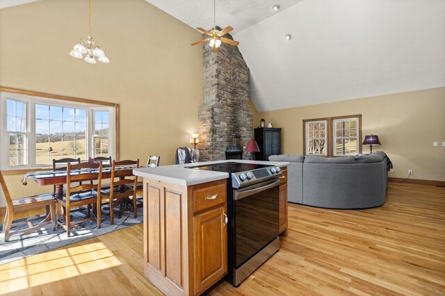 kitchen with light wood-type flooring, stainless steel range with electric stovetop, high vaulted ceiling, and open floor plan