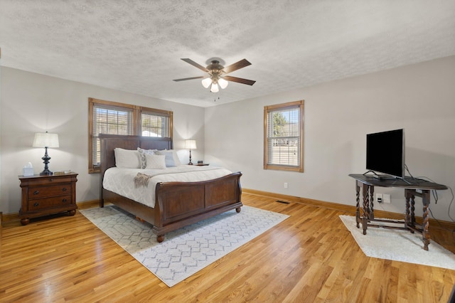 bedroom with light wood-style floors, multiple windows, and a textured ceiling