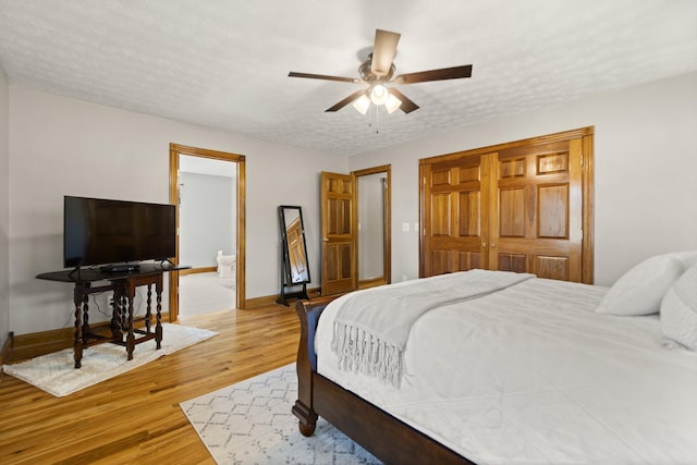 bedroom featuring light wood finished floors, a closet, a ceiling fan, a textured ceiling, and baseboards