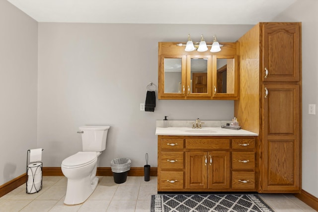 bathroom with toilet, vanity, baseboards, and tile patterned floors