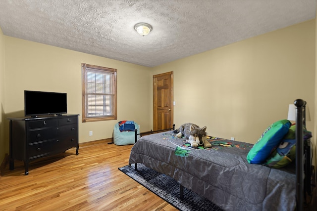 bedroom featuring a textured ceiling, wood finished floors, and baseboards