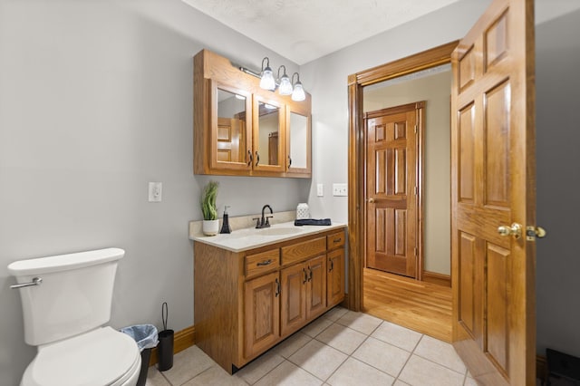 bathroom featuring vanity, tile patterned flooring, toilet, and baseboards