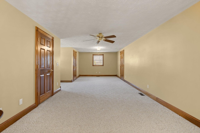 unfurnished room with baseboards, visible vents, a textured ceiling, and light colored carpet