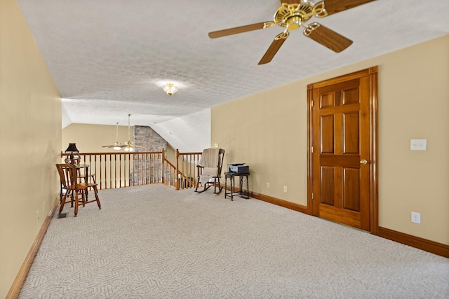 interior space with lofted ceiling, ceiling fan, a textured ceiling, carpet flooring, and baseboards