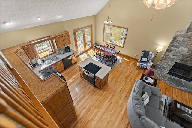 living room with baseboards, a textured ceiling, light wood-type flooring, a fireplace, and a notable chandelier