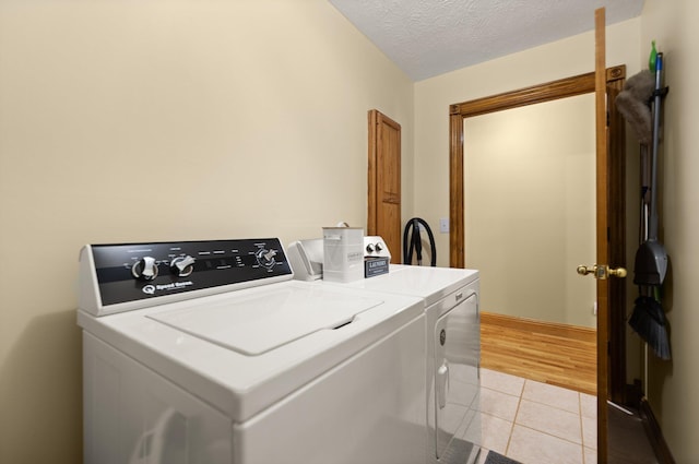 clothes washing area featuring laundry area, independent washer and dryer, a textured ceiling, and light tile patterned floors