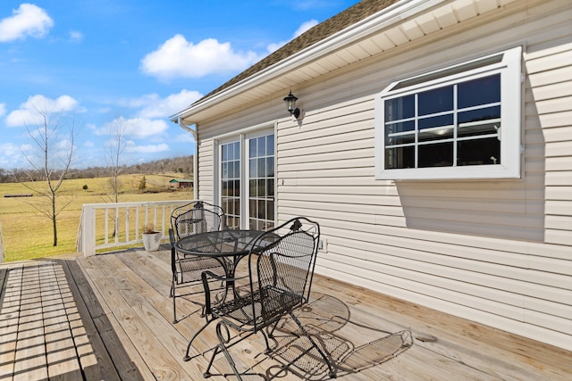 deck with outdoor dining space and a rural view