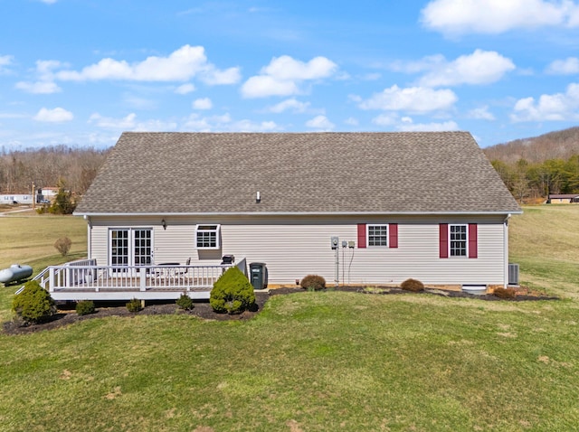 back of house featuring a deck, a lawn, and roof with shingles