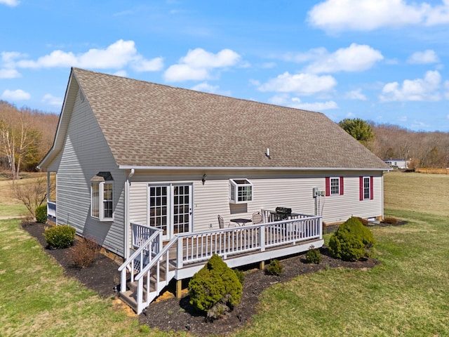 back of house featuring roof with shingles, a deck, and a yard