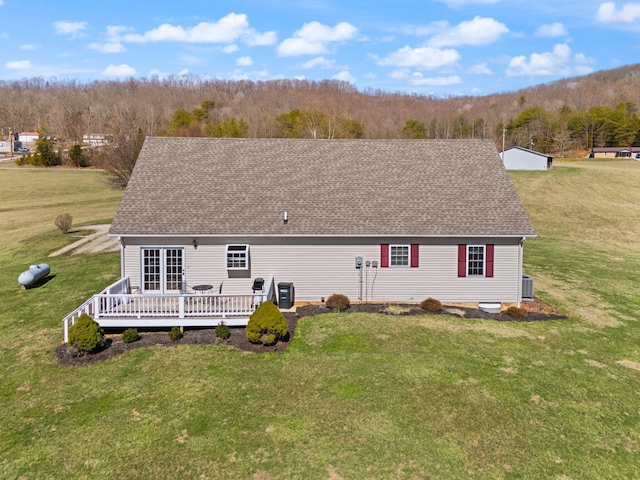 rear view of house with a shingled roof, a lawn, a wooden deck, and central air condition unit