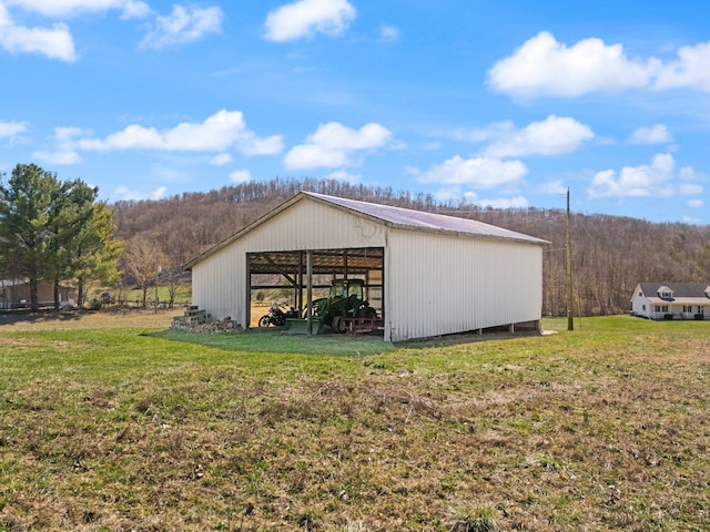 view of pole building with a view of trees and a lawn