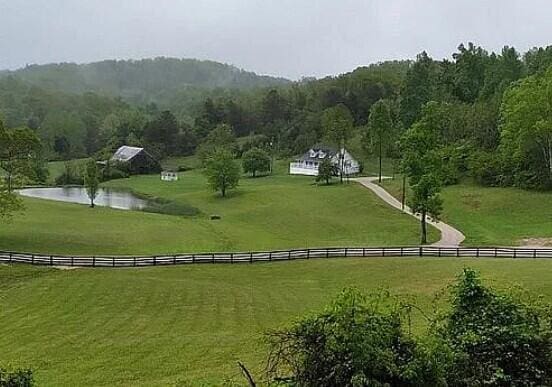 view of home's community featuring a rural view, a lawn, a water view, and a wooded view