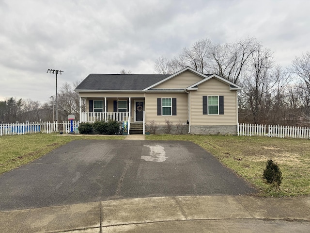 single story home featuring covered porch, a shingled roof, fence, and aphalt driveway