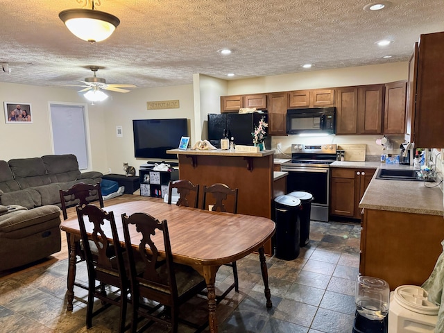 kitchen featuring a kitchen island, open floor plan, light countertops, black appliances, and a sink