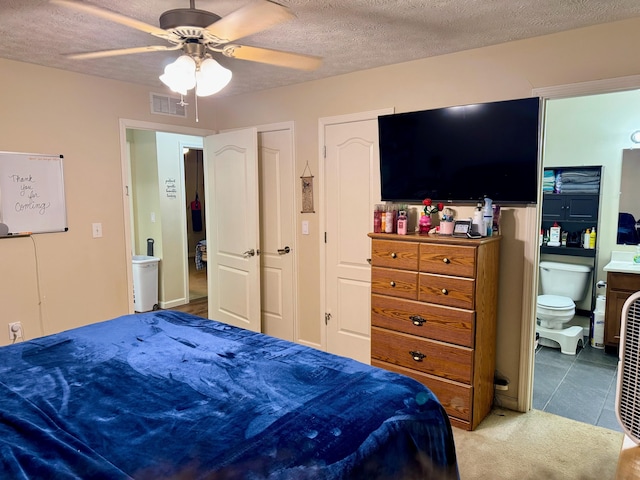 carpeted bedroom featuring multiple closets, ceiling fan, visible vents, and a textured ceiling